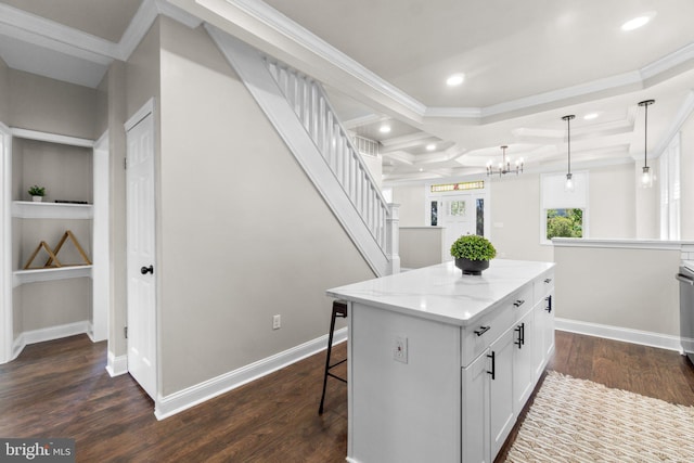 kitchen with a kitchen island, light stone counters, dark wood-type flooring, hanging light fixtures, and white cabinetry