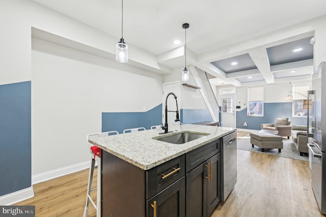 kitchen with light wood finished floors, baseboards, appliances with stainless steel finishes, and a sink