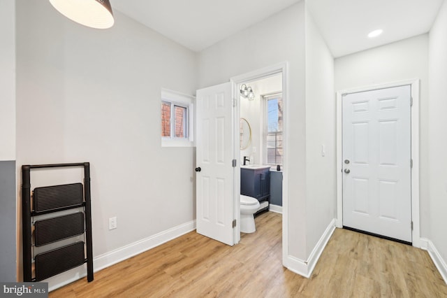 interior space with heating unit, baseboards, and light wood-style flooring