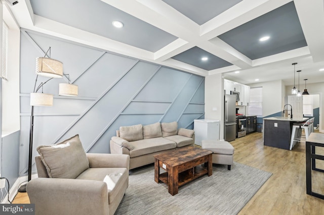 living area with coffered ceiling, beam ceiling, light wood-style flooring, recessed lighting, and a decorative wall