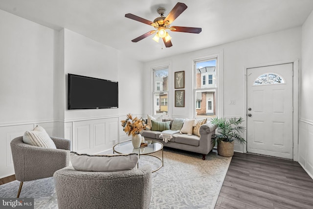 living area with ceiling fan, wainscoting, and wood finished floors