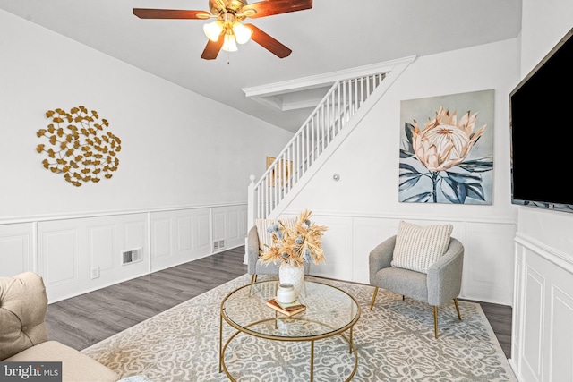 living area featuring visible vents, a ceiling fan, a wainscoted wall, stairway, and wood finished floors