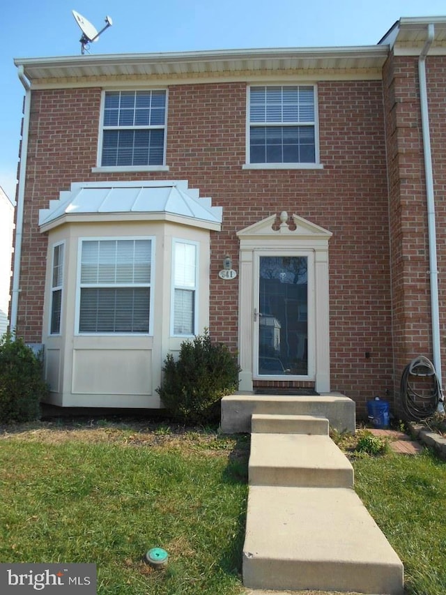 multi unit property featuring a front lawn and brick siding