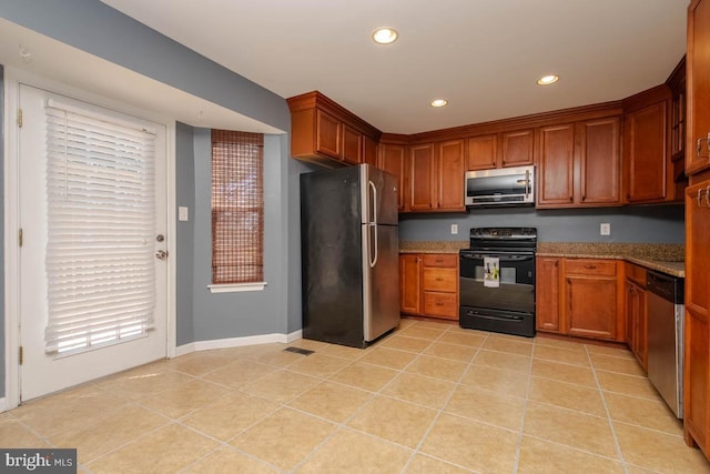 kitchen featuring brown cabinets, light tile patterned floors, recessed lighting, appliances with stainless steel finishes, and light stone countertops