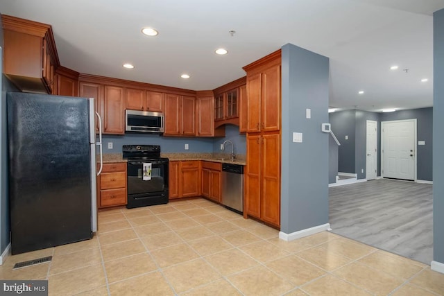 kitchen with brown cabinets, visible vents, appliances with stainless steel finishes, a sink, and light stone countertops