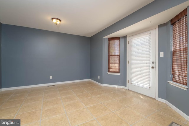 unfurnished room featuring light tile patterned floors, visible vents, and baseboards