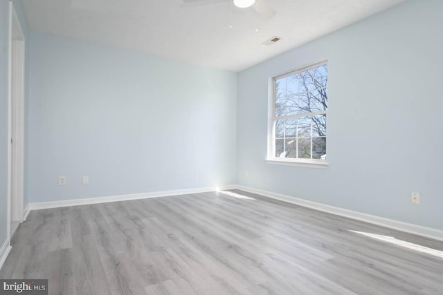 empty room with ceiling fan, wood finished floors, visible vents, and baseboards