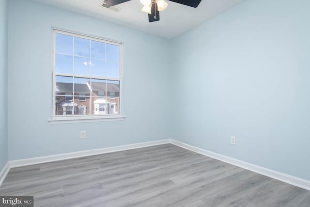 unfurnished room featuring baseboards, visible vents, and wood finished floors