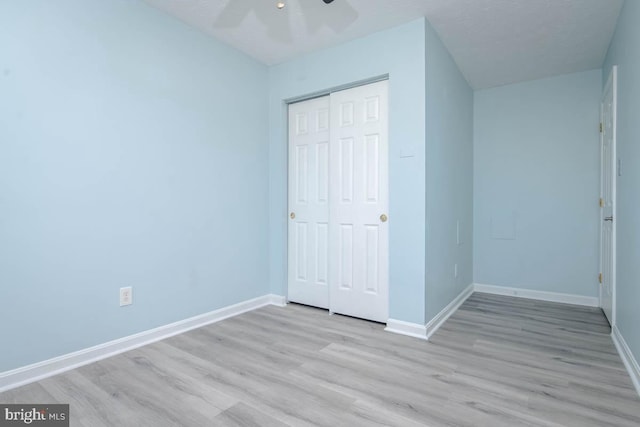 unfurnished bedroom with a closet, wood finished floors, and baseboards