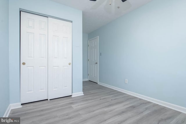 unfurnished bedroom with a closet, ceiling fan, baseboards, and wood finished floors