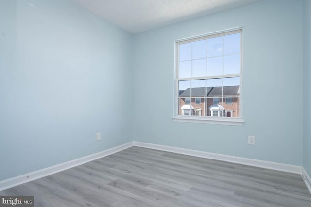 empty room with a textured ceiling, wood finished floors, and baseboards