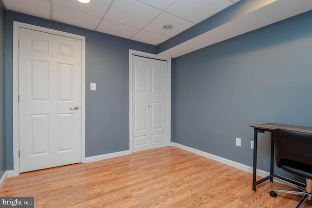 office with light wood-style floors, a paneled ceiling, and baseboards