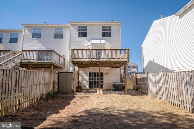 rear view of property with an outbuilding, a storage shed, a fenced backyard, and a wooden deck