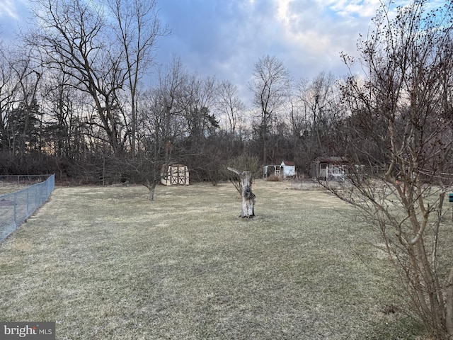 view of yard featuring a shed, fence, and an outbuilding