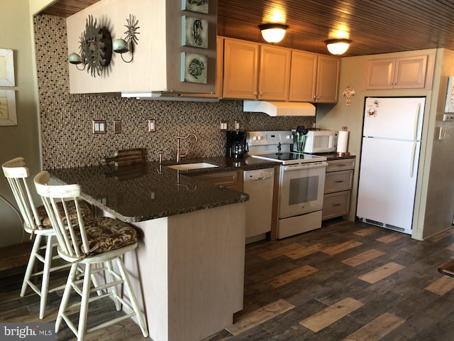 kitchen with white appliances, decorative backsplash, a peninsula, a sink, and exhaust hood