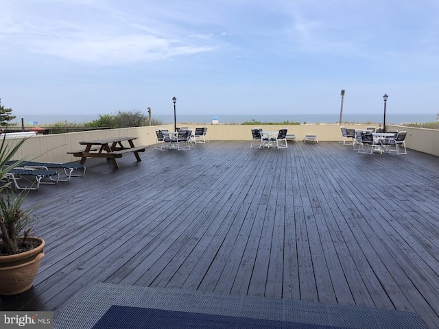 wooden terrace featuring outdoor dining space and a water view