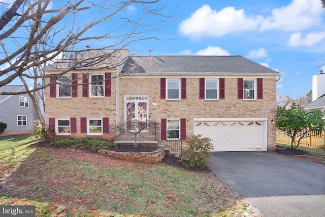 raised ranch featuring an attached garage, brick siding, driveway, and roof with shingles