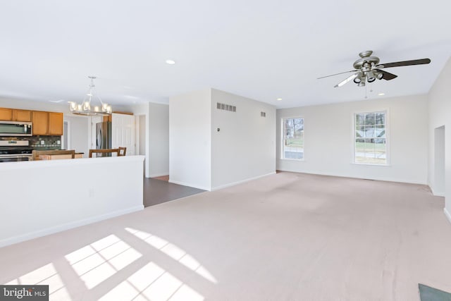 unfurnished living room with recessed lighting, ceiling fan with notable chandelier, visible vents, baseboards, and carpet