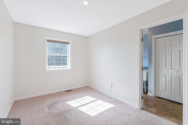 carpeted spare room featuring visible vents and baseboards