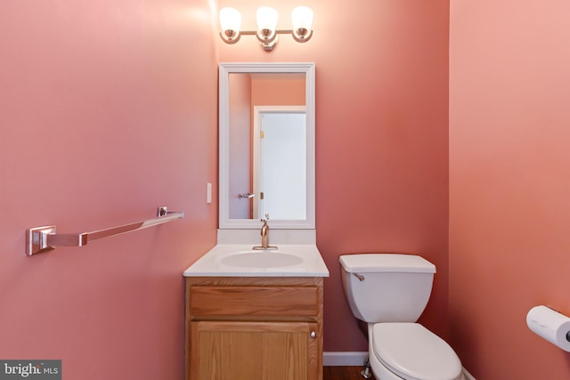 bathroom with baseboards, vanity, and toilet