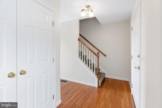 entryway featuring light wood-style flooring, stairs, baseboards, and visible vents