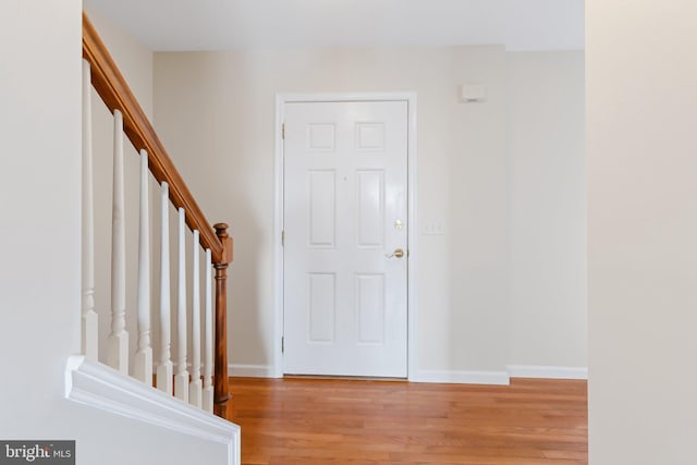 foyer entrance featuring light wood-type flooring, baseboards, and stairs