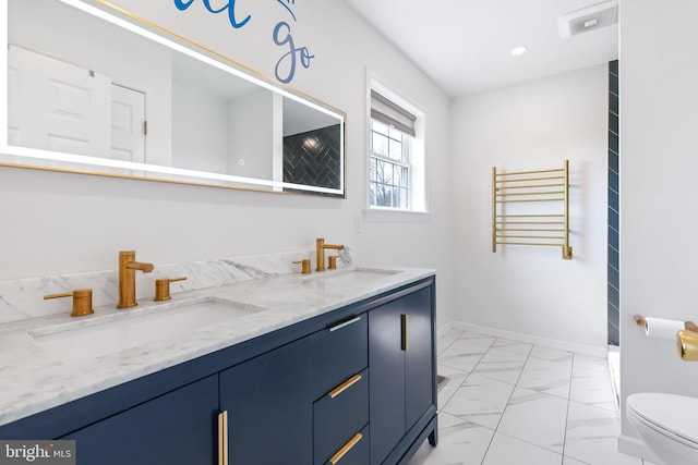 bathroom featuring marble finish floor, double vanity, a sink, and toilet