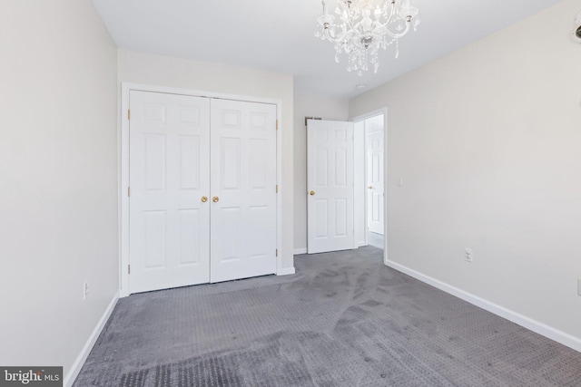 unfurnished bedroom featuring a chandelier, a closet, carpet flooring, and baseboards