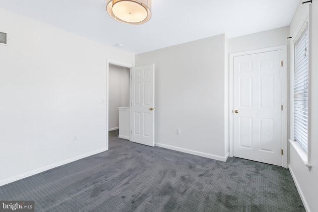 unfurnished bedroom featuring dark colored carpet, visible vents, and baseboards