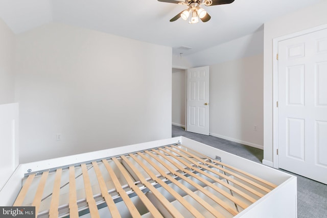 unfurnished bedroom featuring carpet floors, vaulted ceiling, baseboards, and a ceiling fan