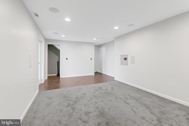 unfurnished room with baseboards, visible vents, wood finished floors, carpet floors, and recessed lighting