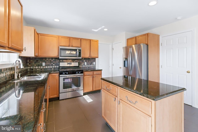 kitchen with a sink, appliances with stainless steel finishes, backsplash, a center island, and dark stone counters