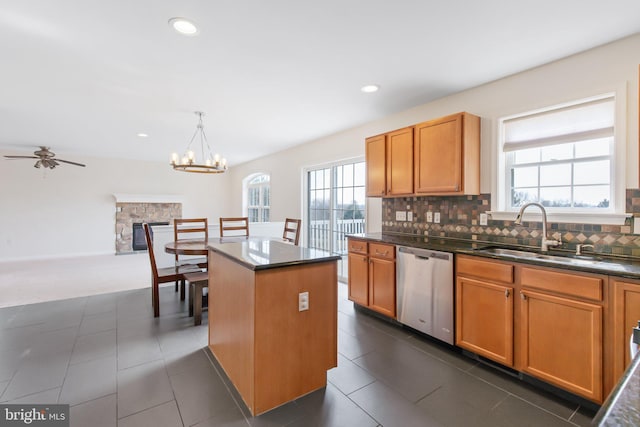 kitchen with stainless steel dishwasher, a sink, a center island, and decorative backsplash