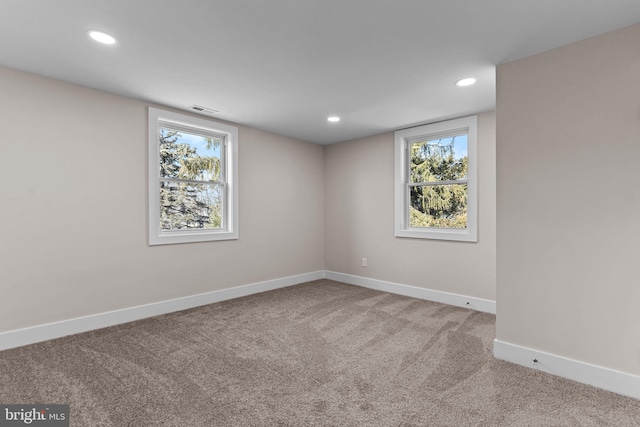 spare room with recessed lighting, carpet flooring, visible vents, and baseboards