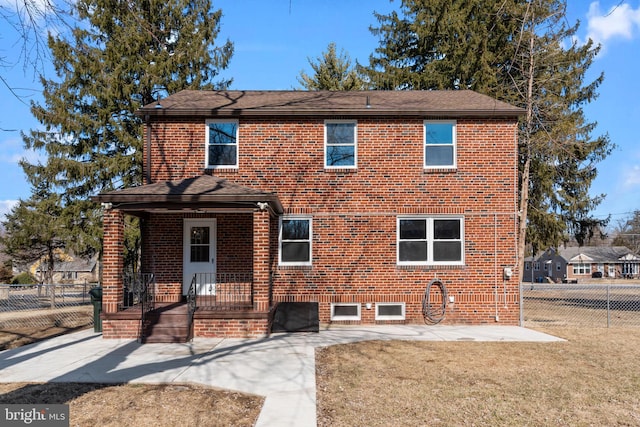 traditional-style home featuring a front yard, brick siding, and fence