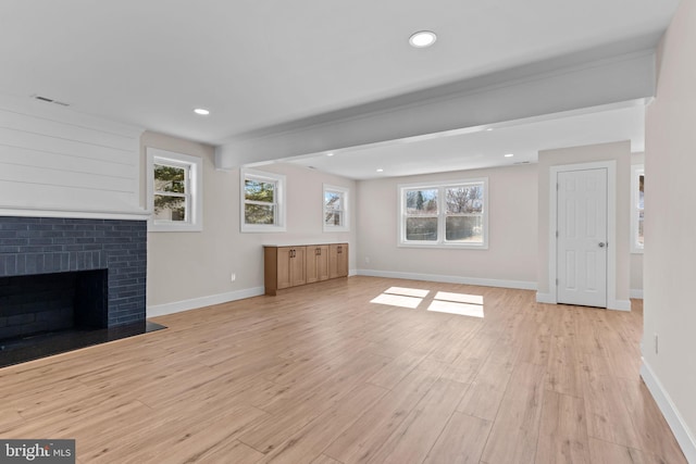 unfurnished living room with light wood-style flooring, a fireplace, visible vents, and baseboards