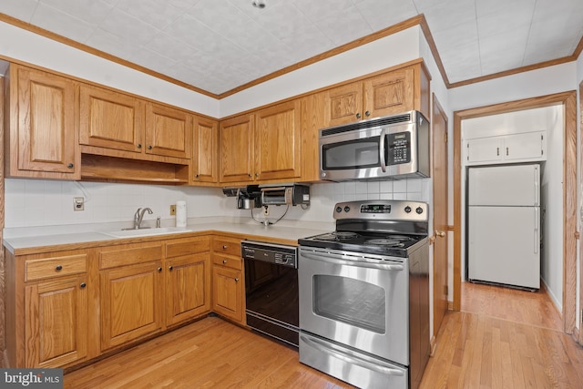 kitchen with light countertops, appliances with stainless steel finishes, a sink, and crown molding