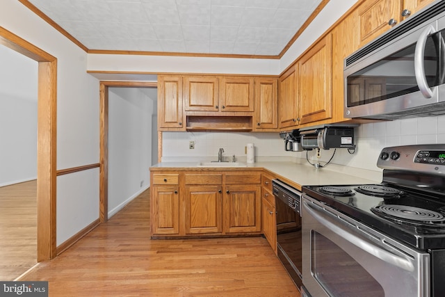 kitchen with light wood-style flooring, a sink, light countertops, appliances with stainless steel finishes, and backsplash