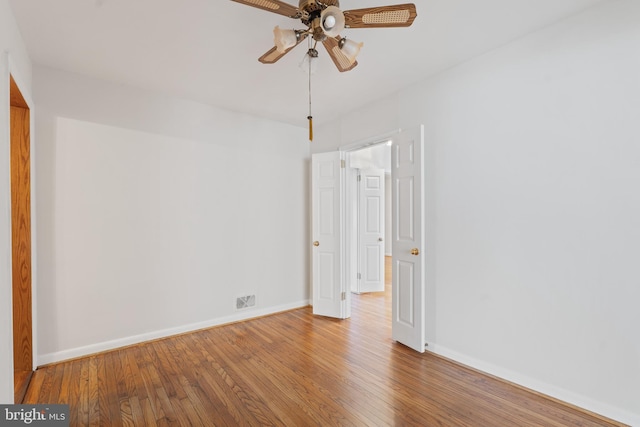 empty room featuring a ceiling fan, baseboards, and wood finished floors