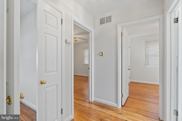 hallway with baseboards, visible vents, and light wood-style floors