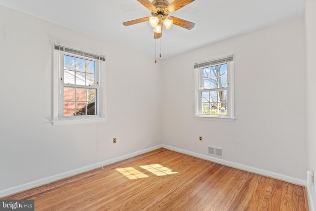 empty room with baseboards, light wood-style floors, visible vents, and a healthy amount of sunlight