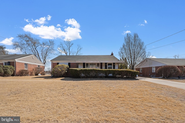 ranch-style house with brick siding, a chimney, and a front yard