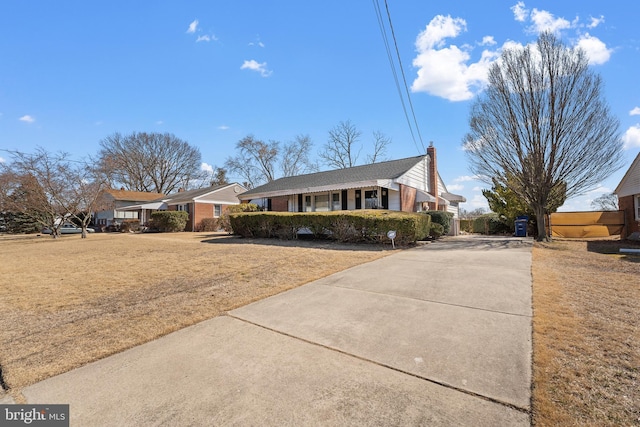 ranch-style home with brick siding, a chimney, and a front yard