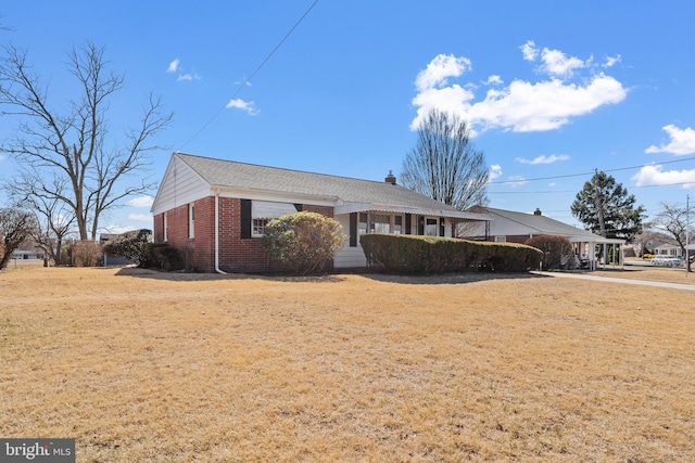 ranch-style home with a front yard, a chimney, and brick siding