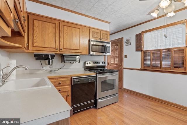 kitchen with stainless steel appliances, a sink, light countertops, and crown molding