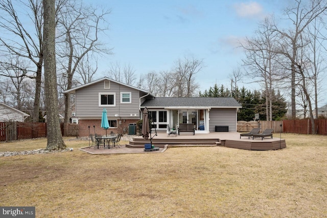 rear view of house featuring a fenced backyard, a yard, a wooden deck, central AC, and brick siding