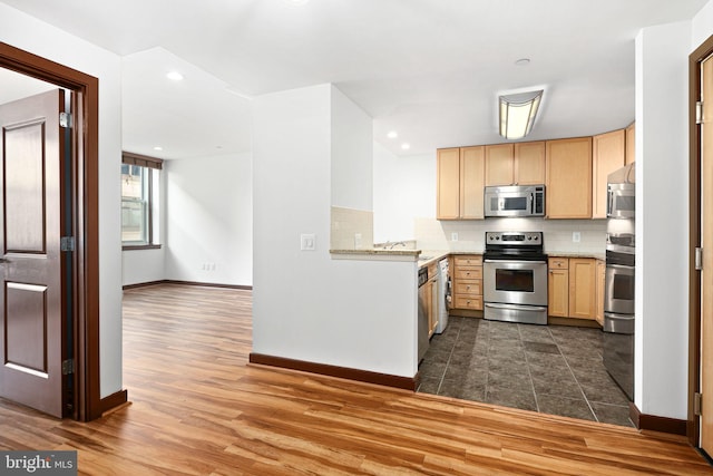 kitchen with dark wood-style floors, light brown cabinetry, appliances with stainless steel finishes, and tasteful backsplash