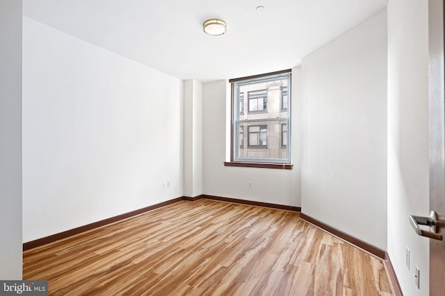 empty room featuring light wood-type flooring and baseboards