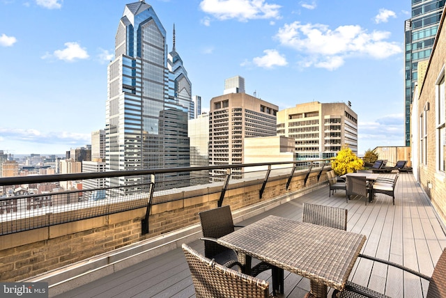 wooden terrace featuring outdoor dining space and a city view