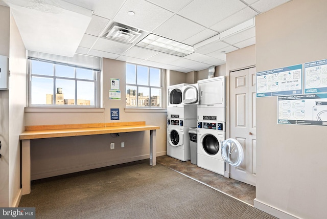 shared laundry area with stacked washer / dryer, washing machine and dryer, visible vents, and baseboards